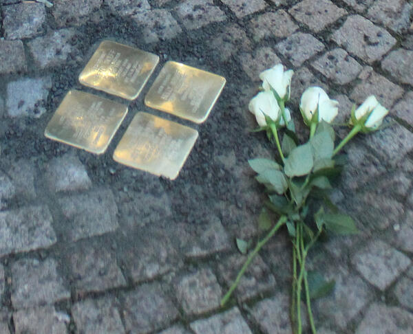 Blumen werden niedergelegt an frisch verlegten Stolpersteinen